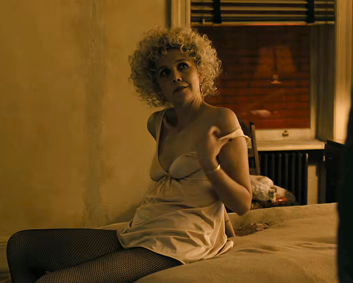 Hollywood actress sitting on a bed preparing for intimate scenes on a movie set.