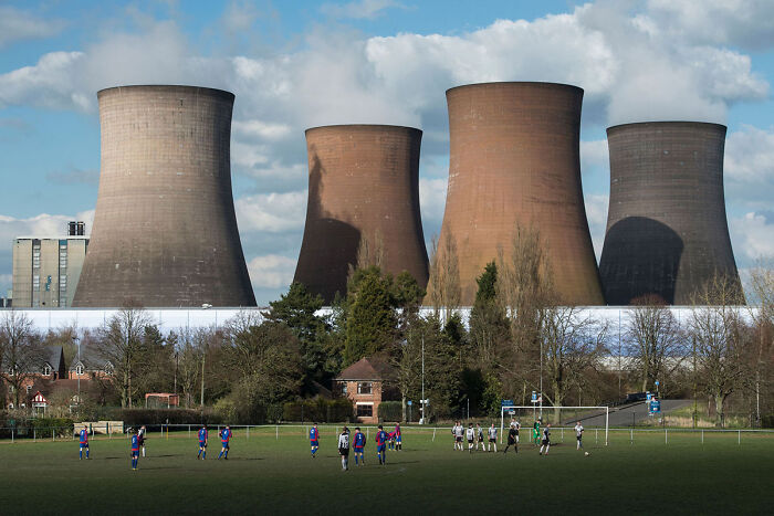 Football players under cooling towers creating surreal glitch scene