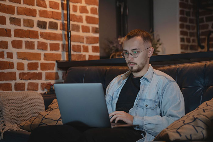 Man focused on laptop working from home in cozy room