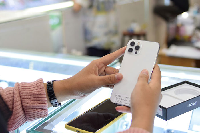 Person unboxing new iPhone phone on glass counter at store