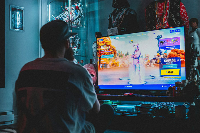 Gamer playing video game on large TV in dark room