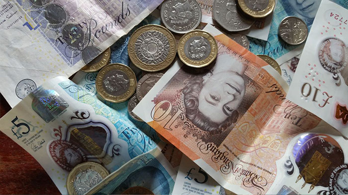 Close-up of British pound coins and banknotes scattered