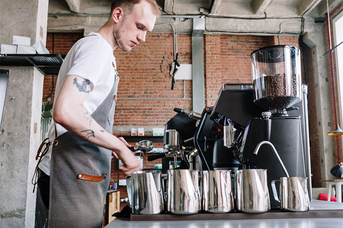 Barista preparing coffee using espresso machine in cafe