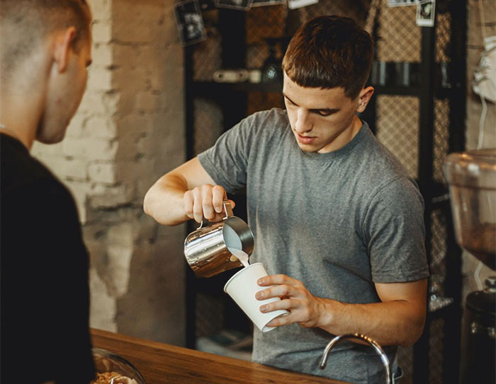 Barista pouring milk foam into cup for coffee