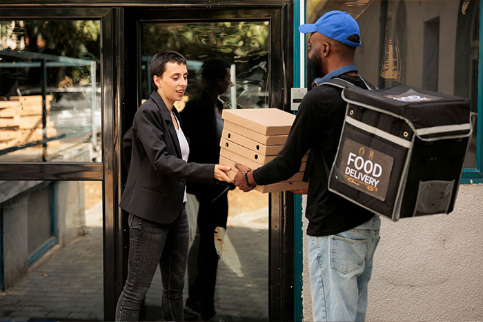 Food delivery person handing pizza boxes to customer