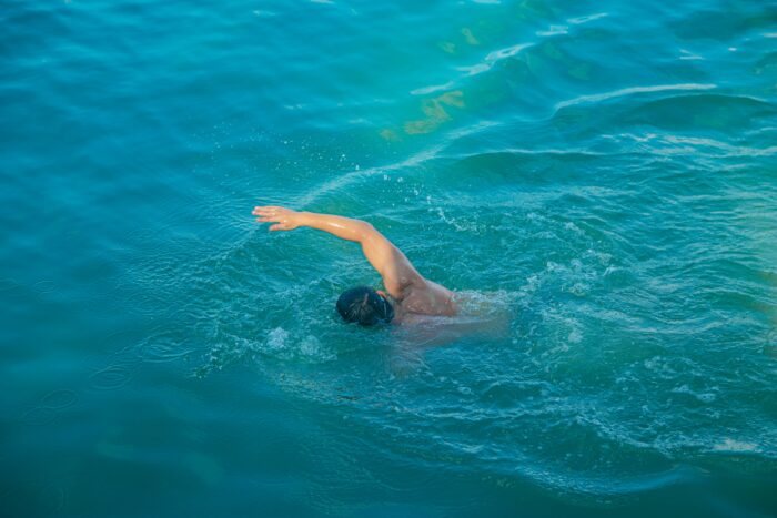 A man swimming in the sea, representing the challenges faced during a walk across countries. A man swimming in the sea, representing the challenges faced during a walk across countries.