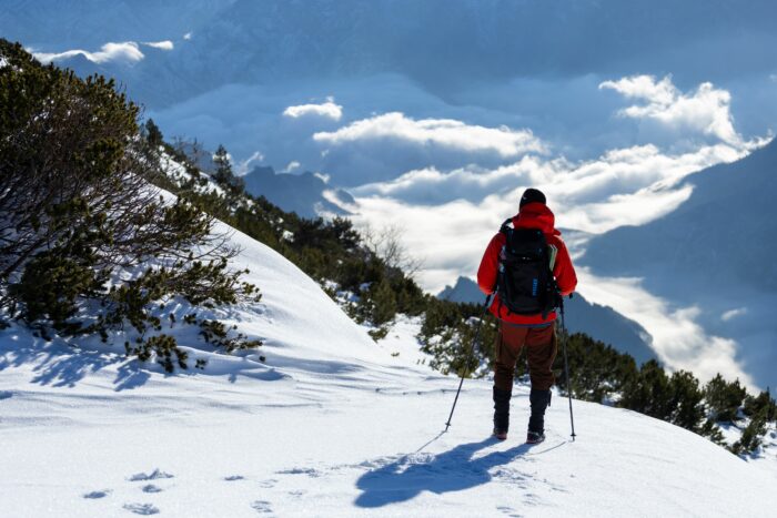 A hiker in a red jacket walking through snowy mountains on a journey across countries. A hiker in a red jacket walking through snowy mountains on a journey across countries.