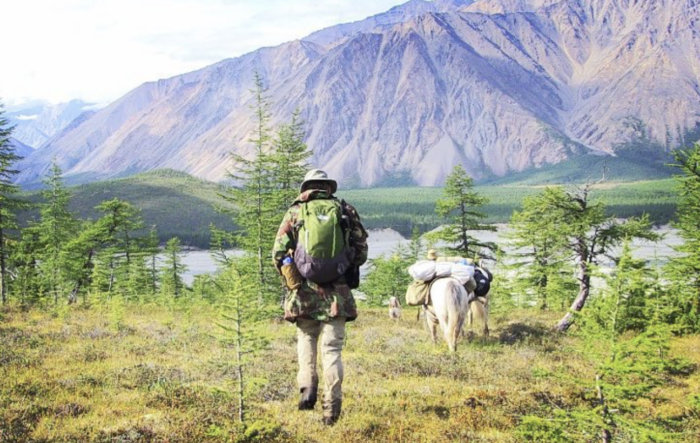 A man with a backpack trekking in the mountains on a long walk across countries. A man with a backpack trekking in the mountains on a long walk across countries.