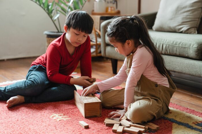 Two children playing together on the floor with wooden blocks Two children playing together on the floor with wooden blocks