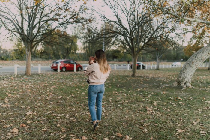 Mother walking in park holding daughter highlighting husband obsession Mother walking in park holding daughter highlighting husband obsession