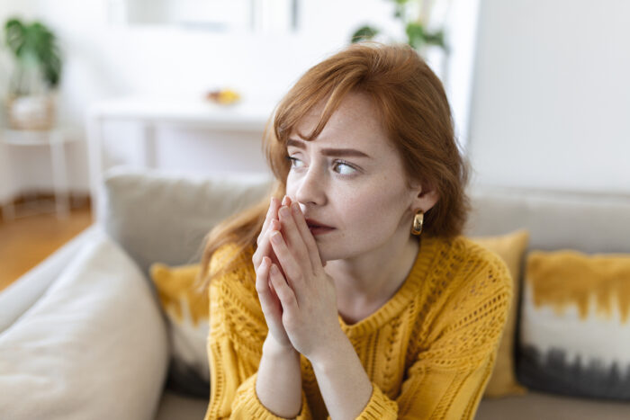 Worried woman sitting on couch contemplating relationship issues Worried woman sitting on couch contemplating relationship issues