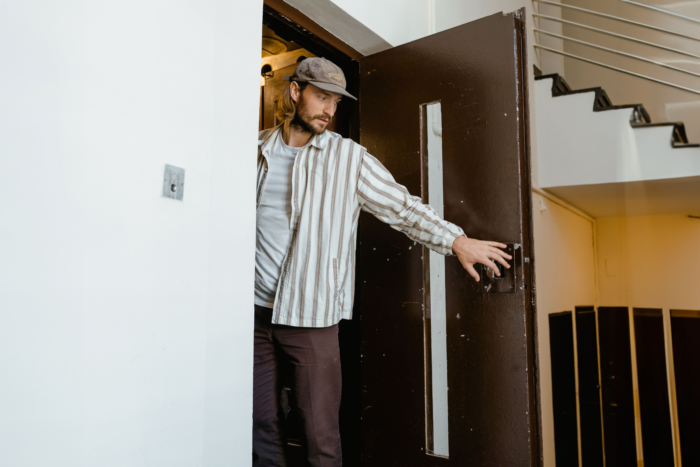 Man opening door cautiously hinting at secret obsession reveal Man opening door cautiously hinting at secret obsession reveal