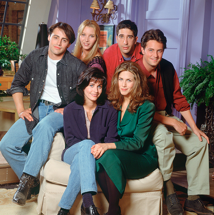 Cast of Friends TV show including Matthew Perry, Courteney C*x, and Jennifer Aniston posed together.