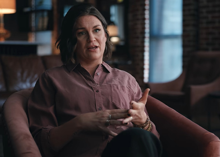 Matthew Perry's sister sitting in an armchair during an interview sharing stories about her brother.