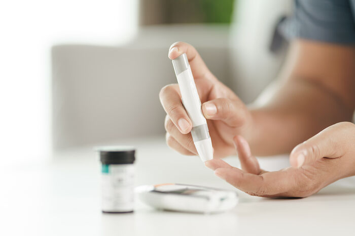 A person using a blood glucose meter to test blood sugar levels, addressing diabetes health problems in Gen Z.