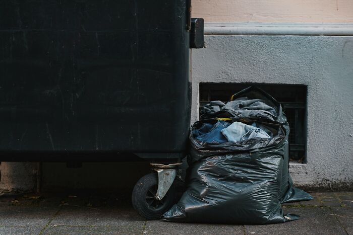 Black trash bags full of discarded items next to a dumpster representing memories of narcissistic parents.