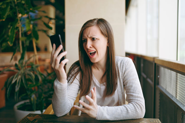 Woman looking shocked and angry at phone call Woman looking shocked and angry at phone call