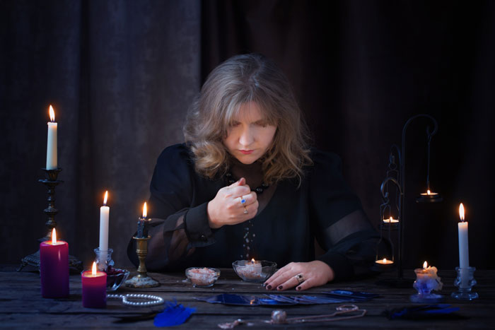 Woman performing ritual with black candles and mystical objects Woman performing ritual with black candles and mystical objects
