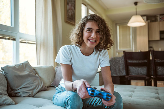 A young girl with a controller playing on game consoles in a living room. A young girl with a controller playing on game consoles in a living room.