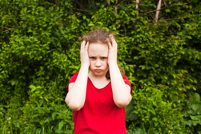 A frustrated young girl in a red shirt representing a jealous sister A frustrated young girl in a red shirt representing a jealous sister