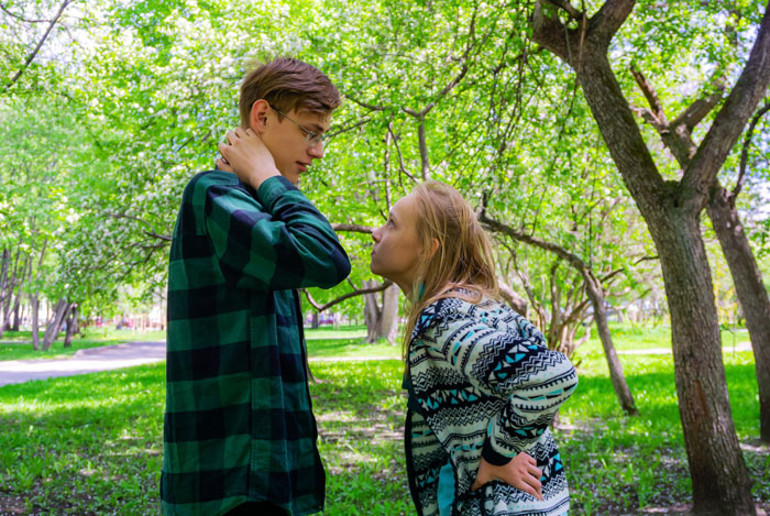 A teen boy and his jealous sister arguing in a park A teen boy and his jealous sister arguing in a park