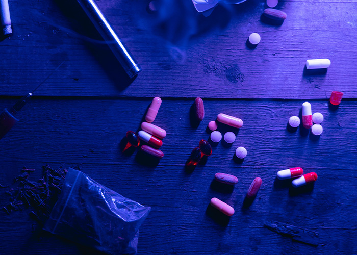 D***s and pills scattered on table symbolizing fashion tragedy