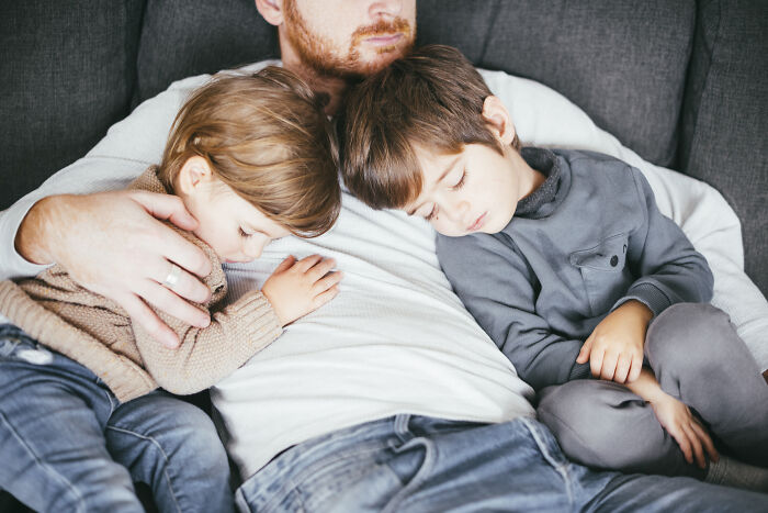 A father napping on a couch with his two young children