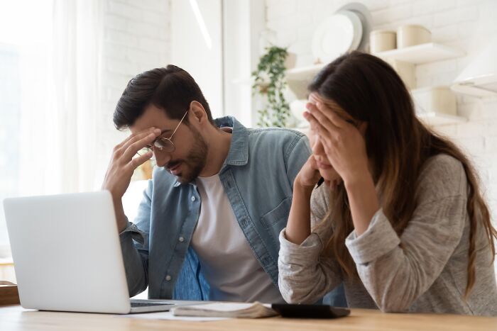 A stressed couple sitting at a desk with a laptop reflecting financial lessons for divorced people