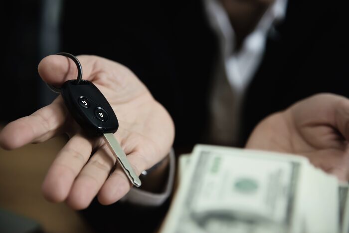 Hands holding a car key and cash symbolizing financial decisions before wedding planning.