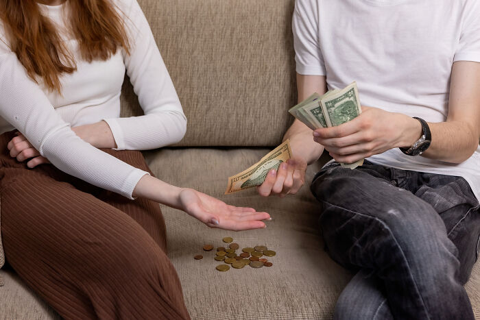 A couple splitting money on a couch, showing financial struggles often faced by divorced people.