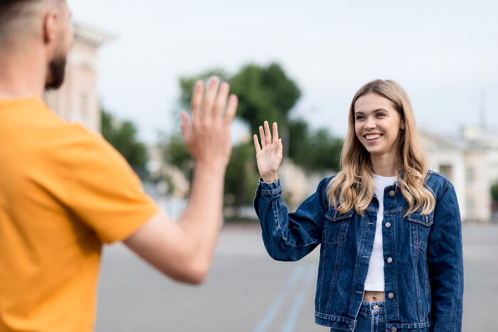Two people waving at each other from a distance, showing social dynamics linked to intelligent insults