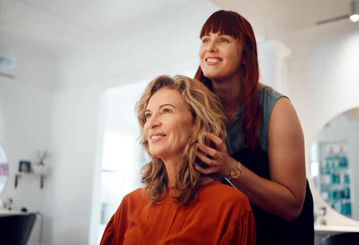 A hairstylist adjusting a woman's hair, representing the subtle art of intelligent insults