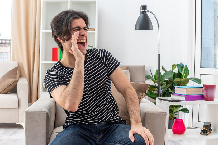 A man yelling while sitting in an armchair, illustrating a moment of intelligent insults.