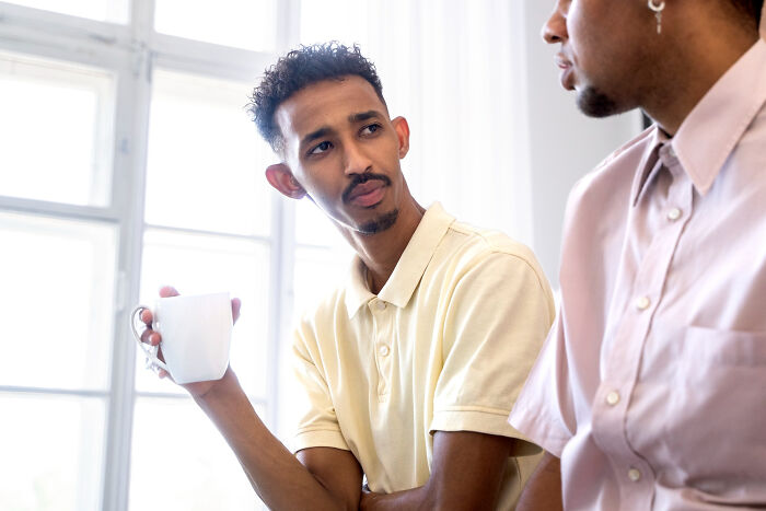A man listening intently with a coffee cup, perhaps hearing intelligent insults.