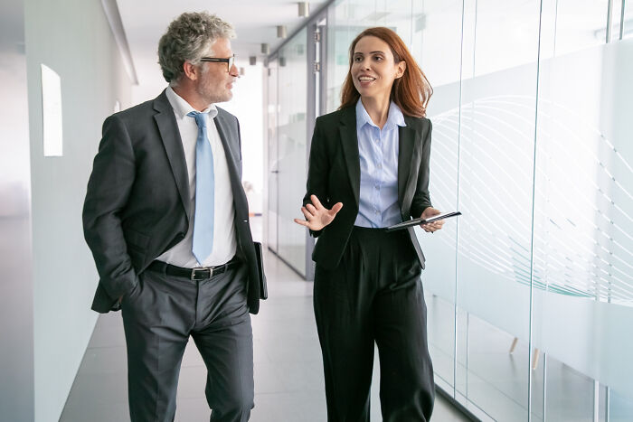 A woman in a suit talking with a colleague, reflecting the concept of intelligent insults in professional settings.