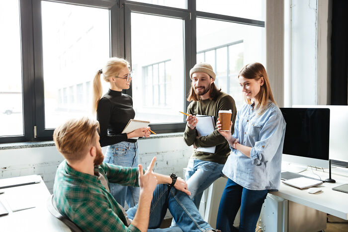 A group of coworkers chatting in an office, discussing examples of intelligent insults