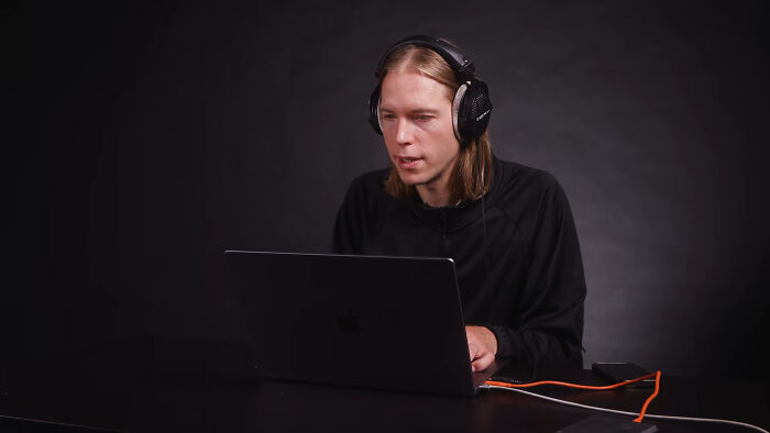 A person wearing headphones looking at a laptop, reading witty examples of intelligent insults