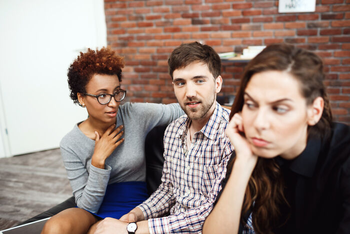 A woman looking annoyed while her friends talk, capturing the reaction to intelligent insults.