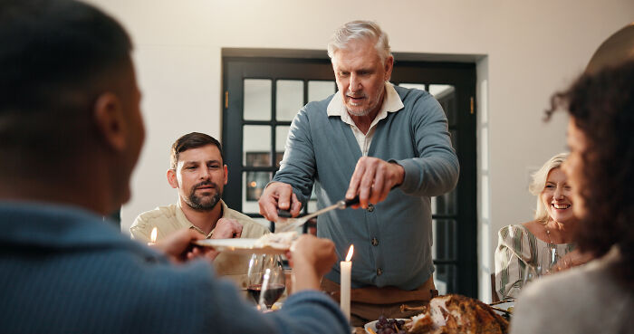 An older man serving food to family members, illustrating interactions with narcissistic parents.
