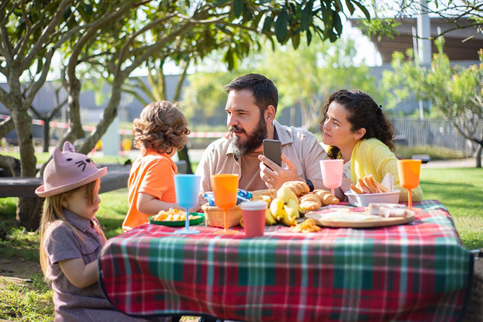 Family with children enjoying a park picnic, illustrating boundaries when a guy keeps pursuing ex.
