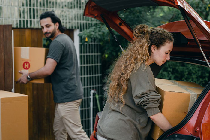 Man and woman packing cardboard boxes into a car trunk, highlighting family conflicts and crossing boundaries.