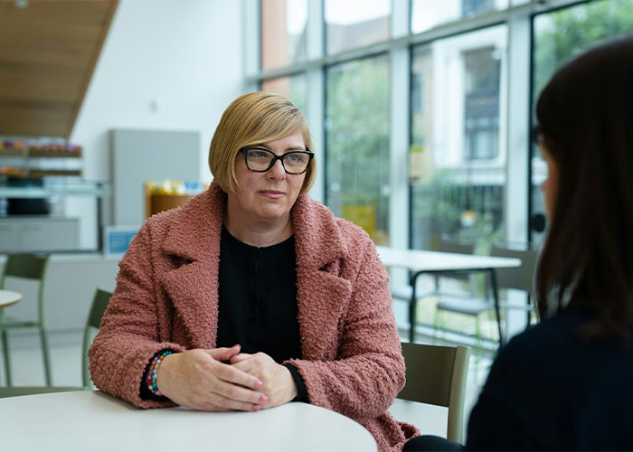 A woman sitting at a caf&eacute; table in a discussion about how her sister helps her ex cross every boundary.