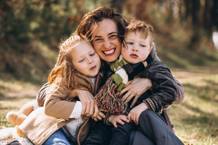 Happy mother hugging her two children outside, showing strong family bonds that keep them from being disowned