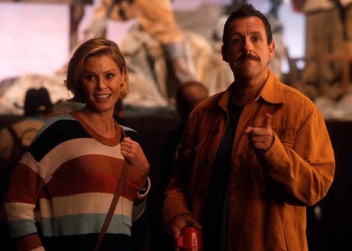 Adam Sandler pointing ahead next to Julie Bowen in a film scene