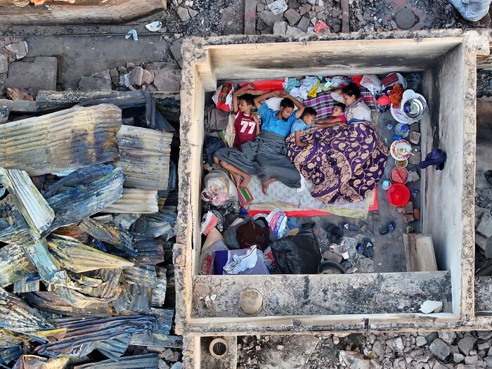 Family resting in small walled area amid ruins and debris