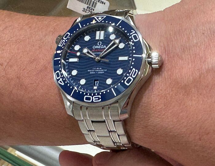 A close-up shot of an Omega Seamaster luxury watch on a wrist, linked to obvious lies.