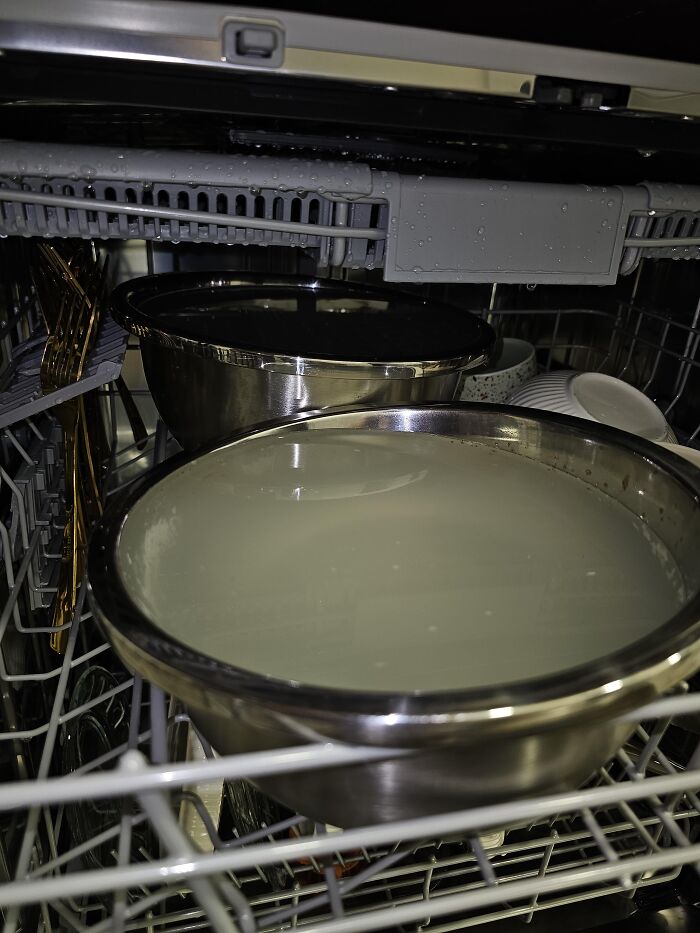 A dishwasher loaded with large metal mixing bowls filled with water, shown as one of many absurd products and situations.