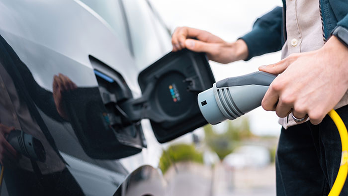 Person plugging charger into electric vehicle for EV charging Person plugging charger into electric vehicle for EV charging