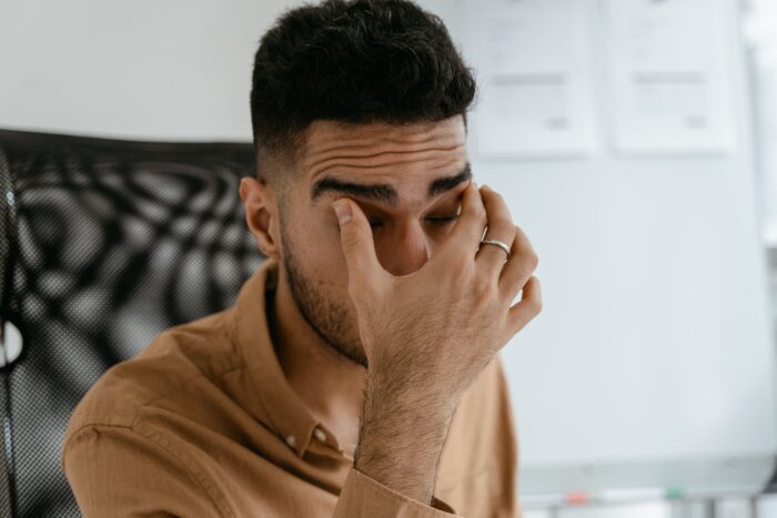 Frustrated man pinching the bridge of his nose, overwhelmed by a driveway parking price tag dispute. Frustrated man pinching the bridge of his nose, overwhelmed by a driveway parking price tag dispute.
