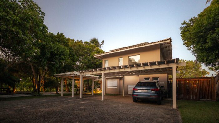 A SUV parked under a covered carport in front of a modern house driveway A SUV parked under a covered carport in front of a modern house driveway
